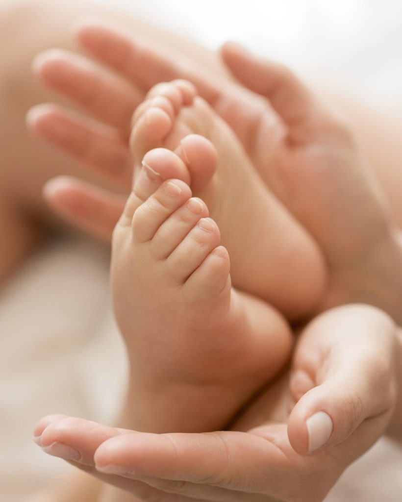 close-up-mom-holding-baby-s-feet-hands